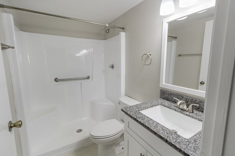A white bathroom with a toilet, sink and shower.