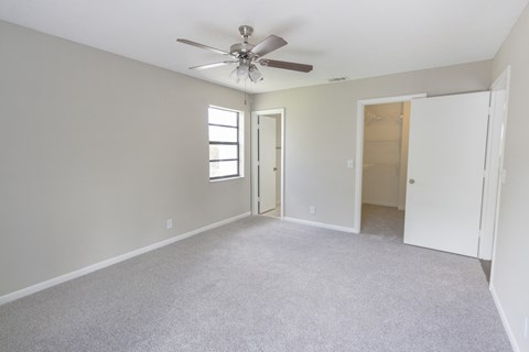 A room with a ceiling fan and carpeted floor.