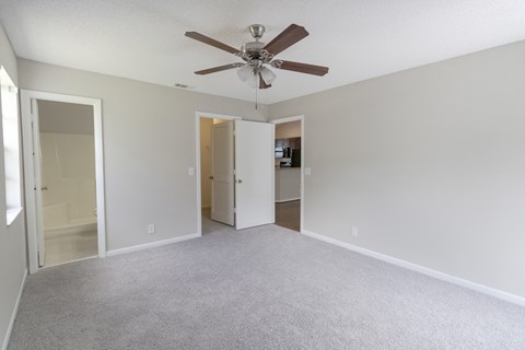 A room with a ceiling fan and carpeted floor.