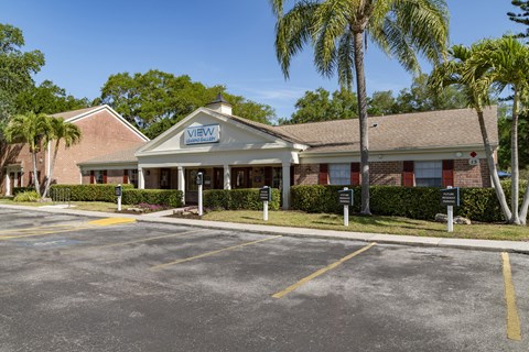 a building with palm trees in front of a parking lot