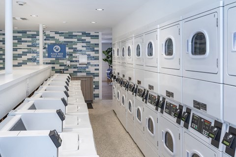 a row of washers and dryers in a laundromat with white machines