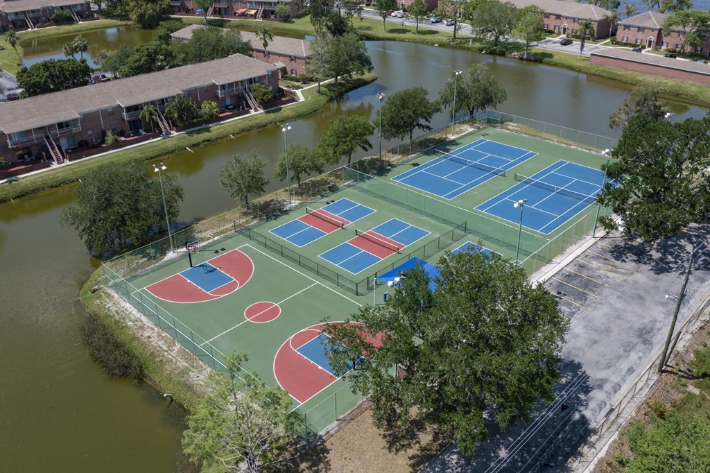 an aerial view of three tennis courts on a municipal court near a body of water