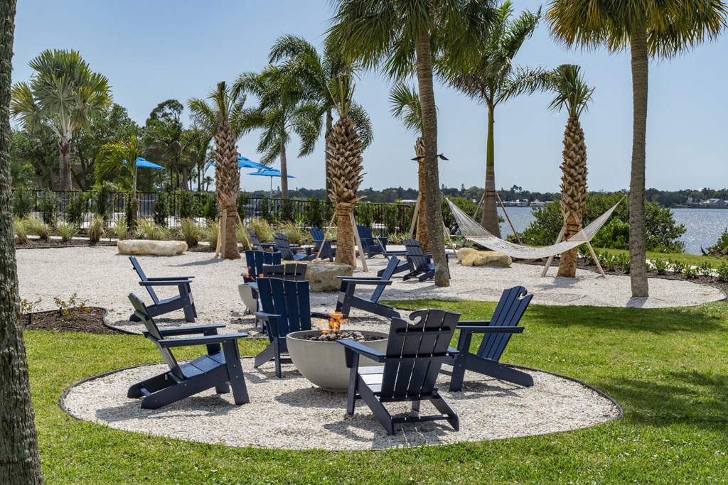 a park with chairs and hammocks and a fire pit