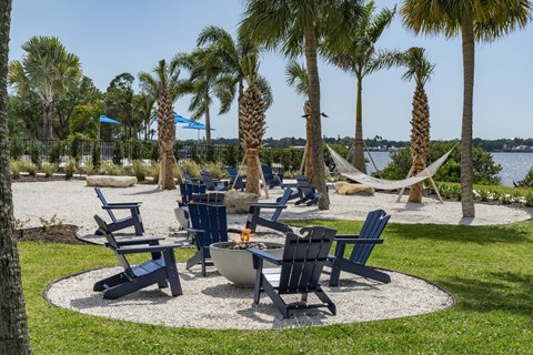 a park with chairs and hammocks and a fire pit