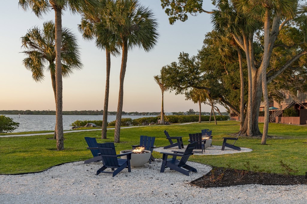 a group of chairs sitting around a fire pit next to the water