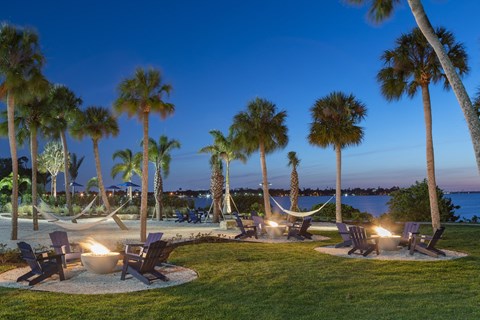 a patio with chairs and palm trees at night