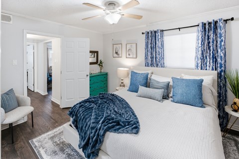 A bedroom with a bed covered in a blue blanket and a ceiling fan.