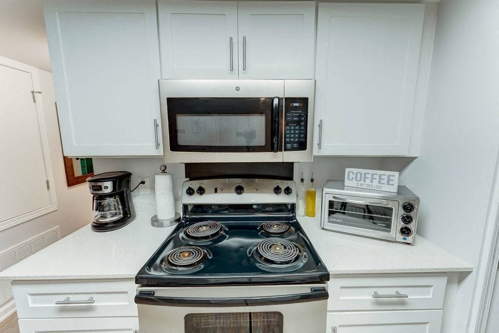 a kitchen with a stove top oven next to a microwave at Juniper Springs Apartments, Austin, TX