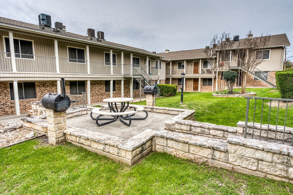 a patio with a table and a fire pit in front of an apartment building