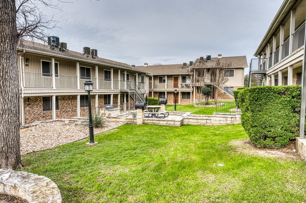 the backyard of an apartment building with a yard and grass
