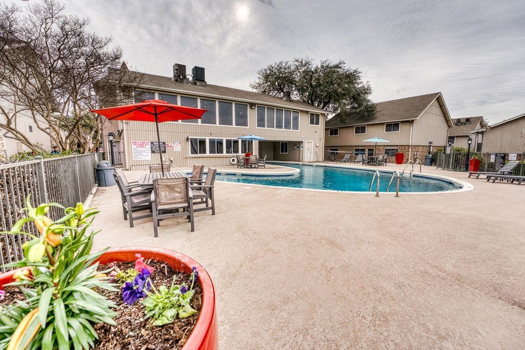 a backyard with a pool and patio with tables and umbrellas