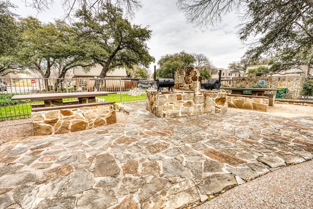a stone patio with a stone fireplace and benches