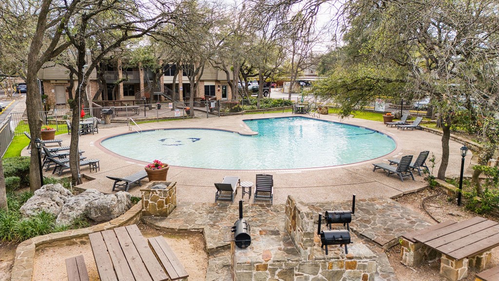 a resort style swimming pool is surrounded by benches and trees