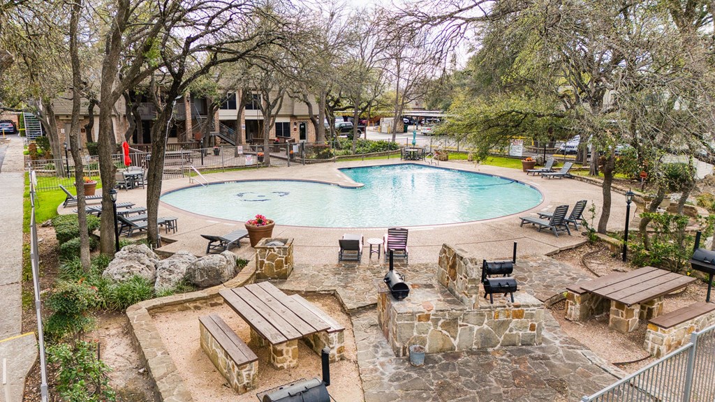 a resort style swimming pool with trees and chairs around it
