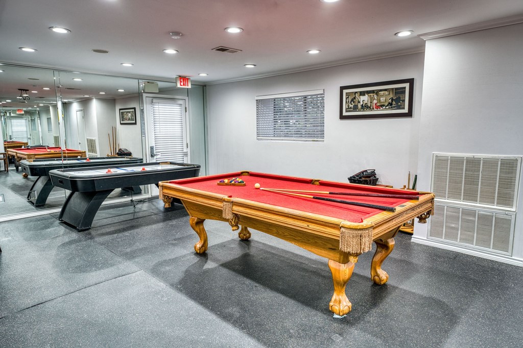 two pool tables in a game room with other billiard tables