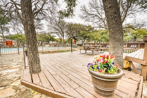 Wooden deck area with flower planter and picnic tables at Le Montreaux Apartments, Austin, 78759