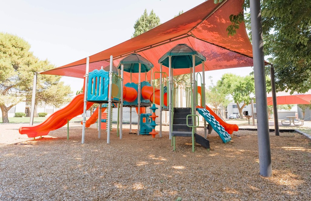 a playground with a swing set and slides  at Cantera Apartments, El Paso TX 79935