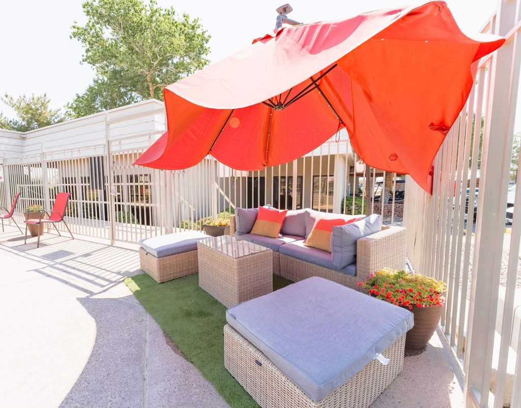 pool deck with wicker furniture and an umbrella  at Cantera Apartments, El Paso TX 79935