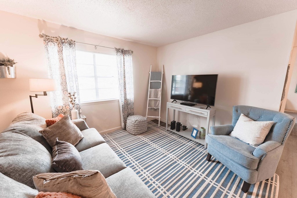 a living room with a gray couch and a blue chair  at Cantera Apartments, El Paso TX 79935
