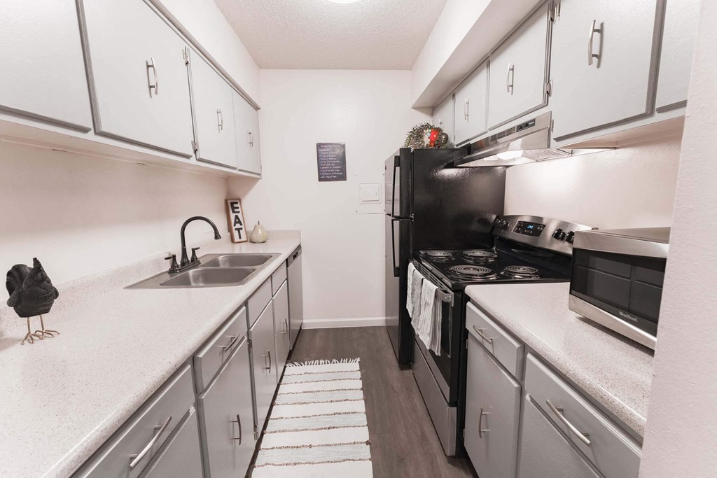 a kitchen with white cabinets and a black stove top oven  at Cantera Apartments, El Paso TX 79935