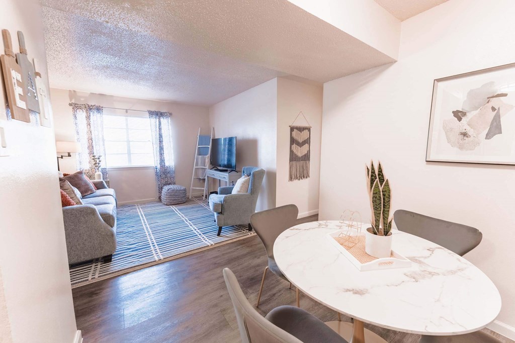 a dining area with a round table and chairs and a living room with a couch  at Cantera Apartments, El Paso TX 79935