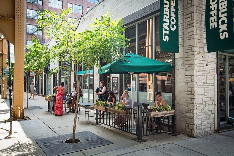people sitting at tables under umbrellas outside of a building