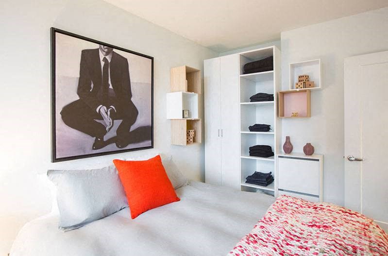 a bedroom with a bed with an orange pillow and a picture