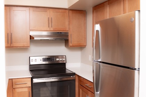 A modern kitchen with a stainless steel refrigerator and black stove.