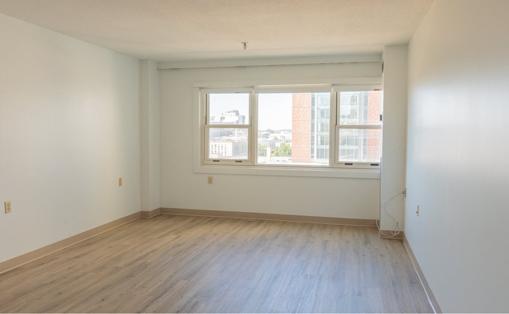 an empty room with a window and wooden floors