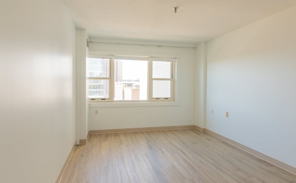 an empty room with a window and wooden floors