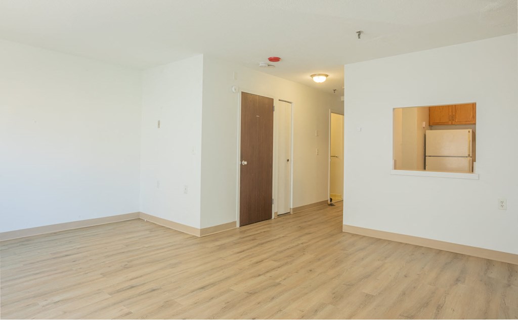a bedroom with white walls and wood floors and a door