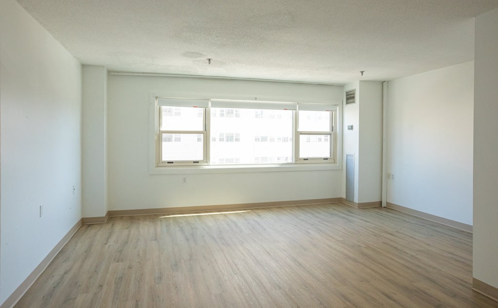 the living room of an empty apartment with wood floors and a large window