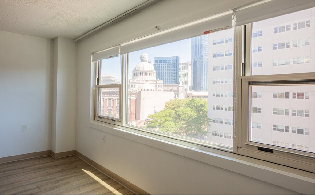 an empty living room with a large window and a city view