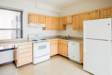 an empty kitchen with white appliances and wooden cabinets