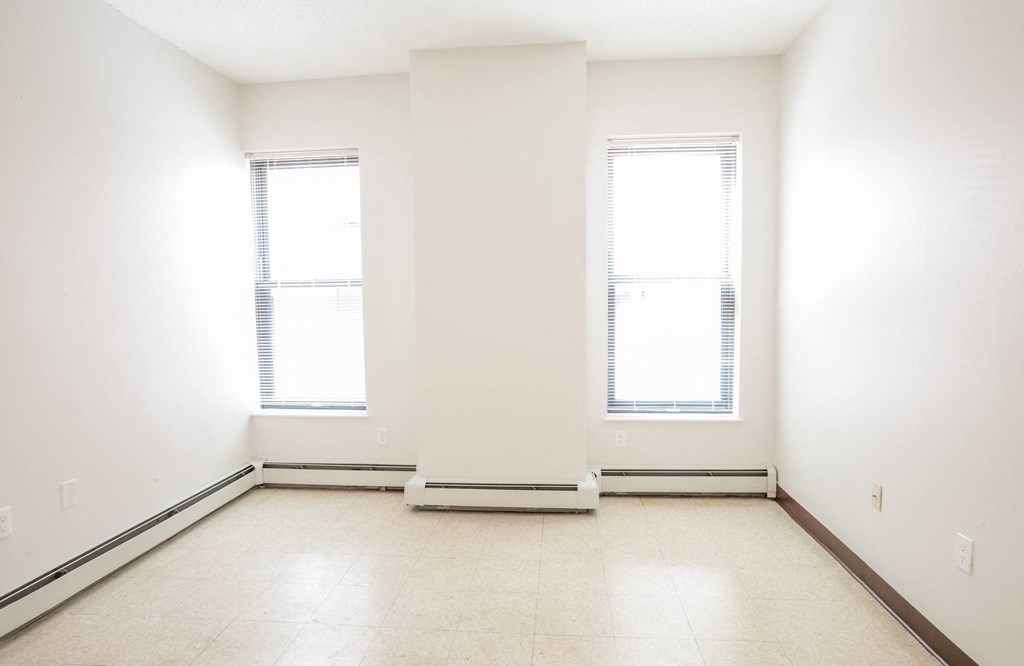 an empty room with two windows and a tiled floor
