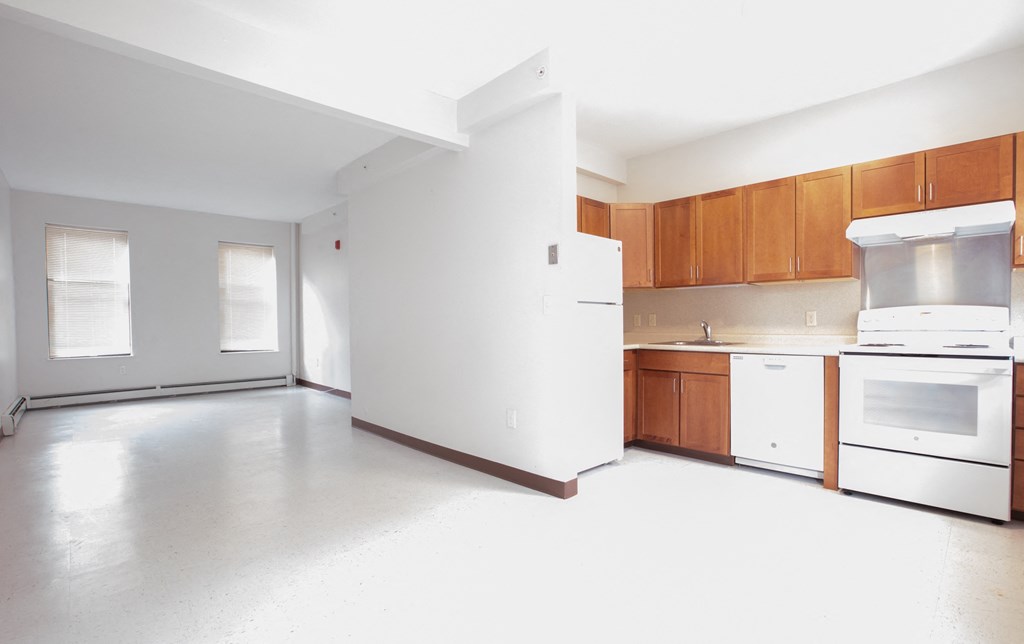 an empty kitchen with white appliances and wooden cabinets