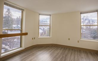 an empty living room with three windows and a wood floor