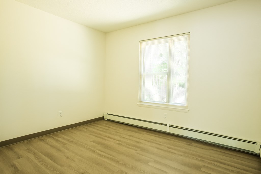 an empty room with wooden floors and a window