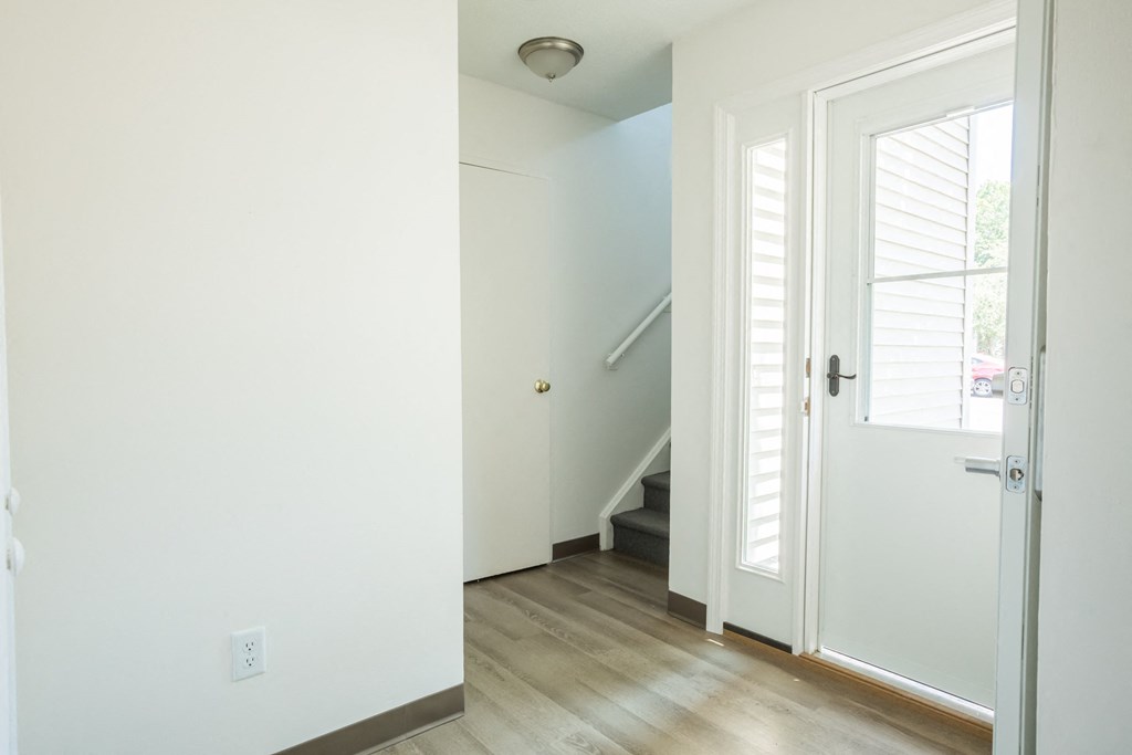 an open door leading to a staircase in a home with white walls and wood floors