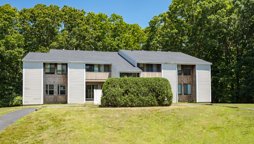 the front of a white house with trees in the background