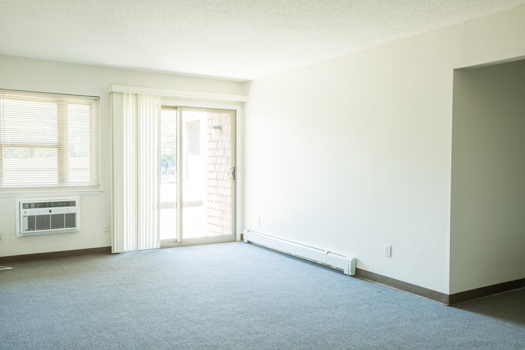 an empty living room with a door to a balcony