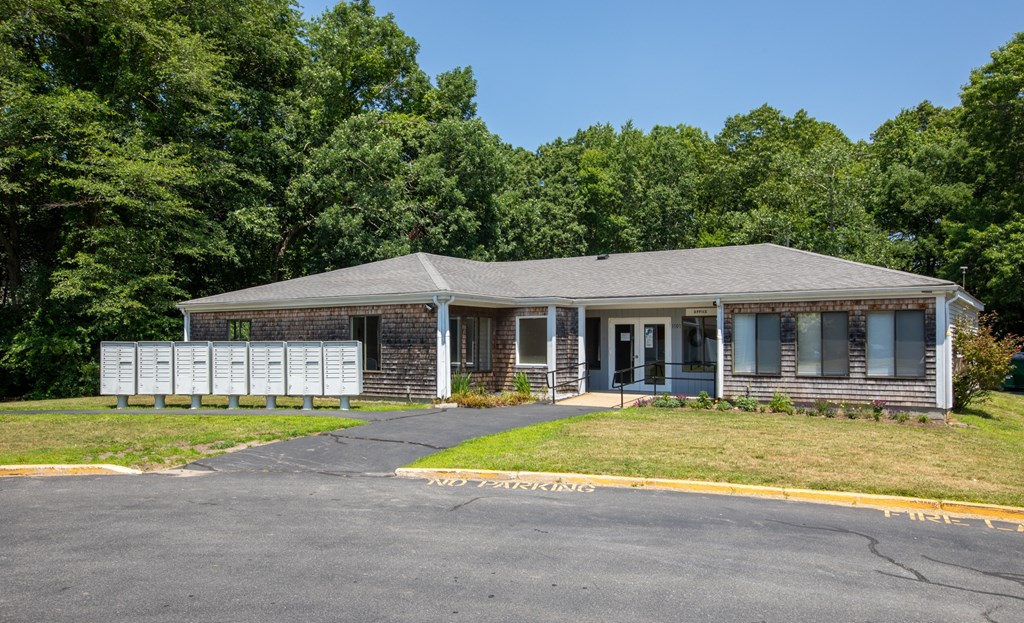 a small brick house with blue shutters and a road in front