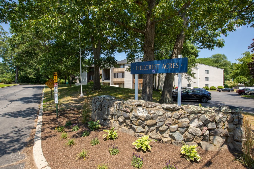 a street sign in front of a stone wall and trees