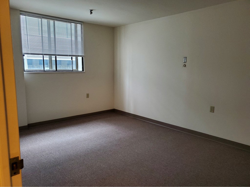 an empty room with a window and a carpeted floor