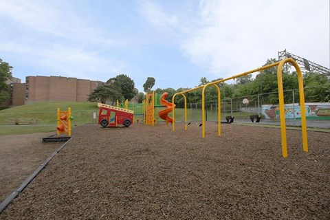 A playground with a red and yellow swing set.