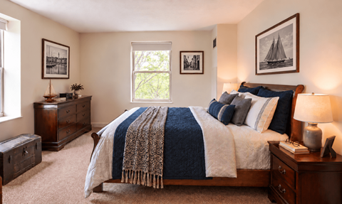 A bedroom with a large bed, a wooden dresser, and a window.