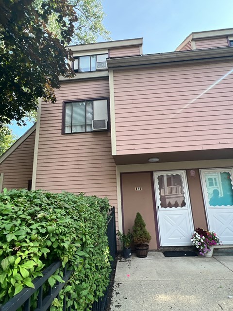 A house with a brown siding and a white door with a window above it.