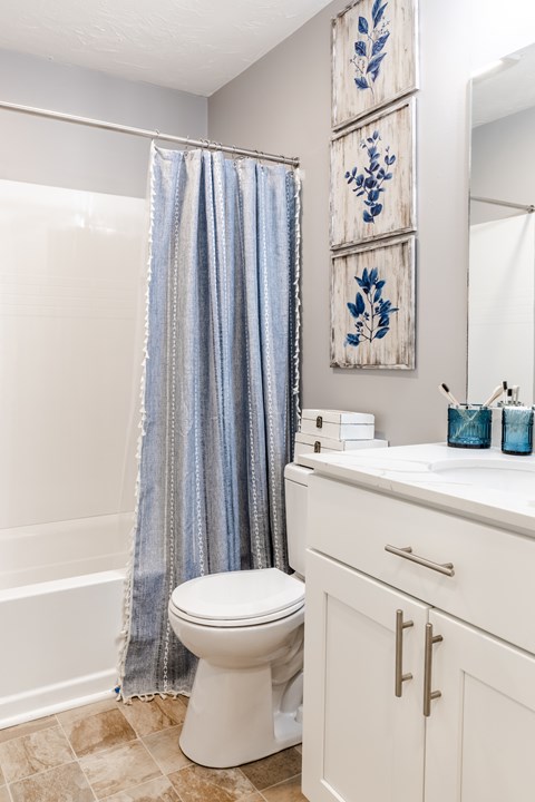 A white toilet with a blue shower curtain in the background.