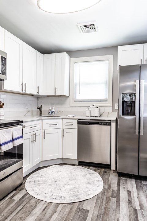 A modern kitchen with white cabinets and stainless steel appliances.