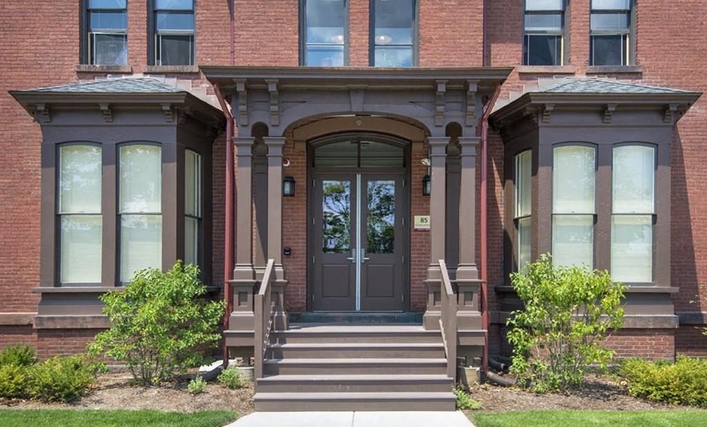 the front of a brick house with a door and stairs